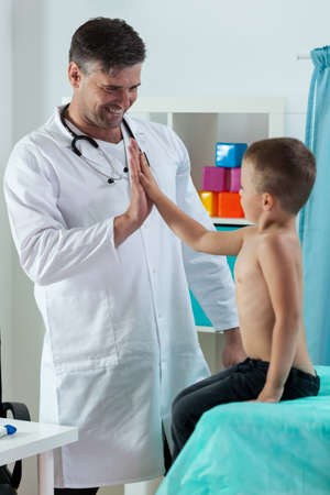 Cheerful friendly pediatric doctor giving boy a fiveの写真素材