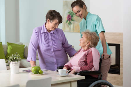 Two aged women and young nurse spending together happy afternoon