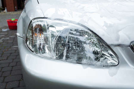 White soap suds on a headlight of silver carの写真素材