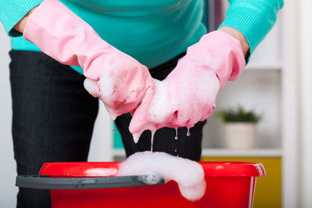 Close-up of older woman's hands and a bucket of foam