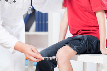 Doctor chekcing the little boy's knee reaction