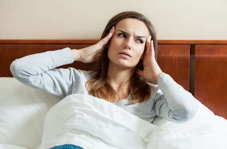 Image of woman having migraine lying in bedの写真素材