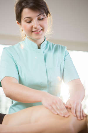 Young beautiful physiotherapist doing neck massageの写真素材