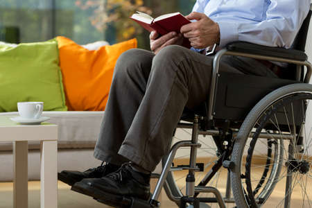 Close-up of man using wheelchair reading bookの写真素材