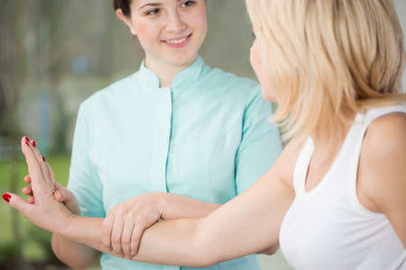 Young physiotherapist and her patient's wrist exerciseの写真素材