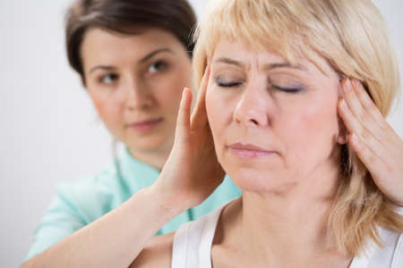 Young physiotherapist helping her patient with head exerciseの写真素材