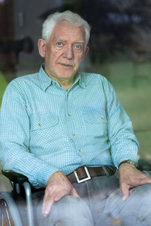 Sad elderly sick man sitting on the wheelchair