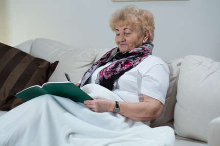 Portrait of senior woman doing crossword puzzleの写真素材