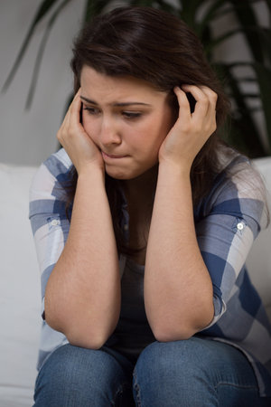 Young depressed woman sitting on the couchの写真素材