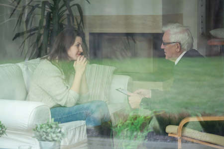Elder therapist consulting young patient at homeの写真素材