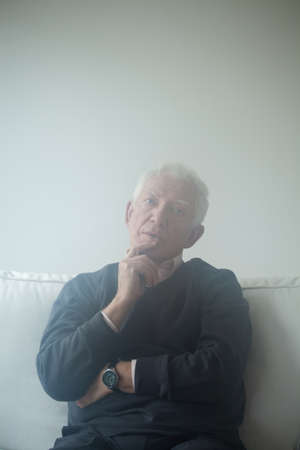 Sad man sitting on the sofa and thinking about problems