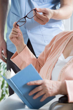 Close-up of male nurse giving the glasses to older ladyの写真素材