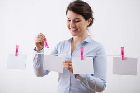 Young woman hanging the cards on clothesline by clothespinsの写真素材