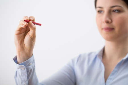 Close-up of young woman writing on glass boardの写真素材