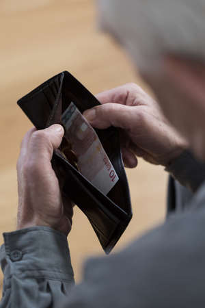 Close-up of elderly man's last banknote in wallet