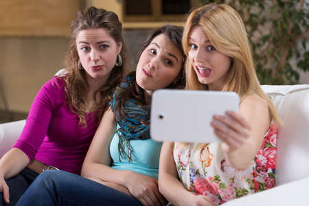 Three best friends doing funny faces to photoの写真素材