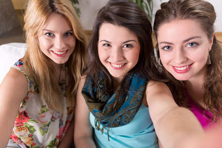 Three attractive smiling girls taking a nice photo of themselves