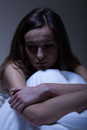 Woman with depression at night in her bedの写真素材