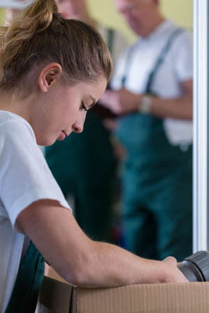 Close-up of young woman packing the box in production hall