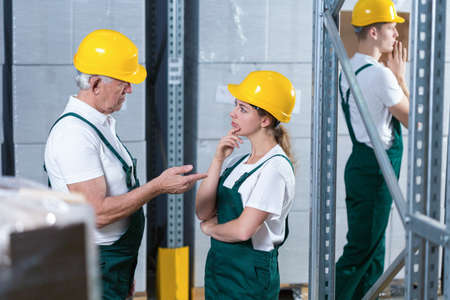 Young woman in helmet talking to her older supervisorの写真素材