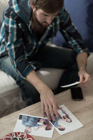 Young handsome sad man looking at old photos