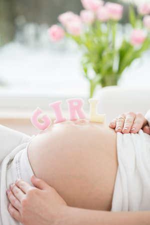 Close-up of colorful letters set on pregnant belly