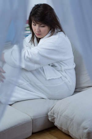 Photo of young pretty worried woman sitting aloneの写真素材