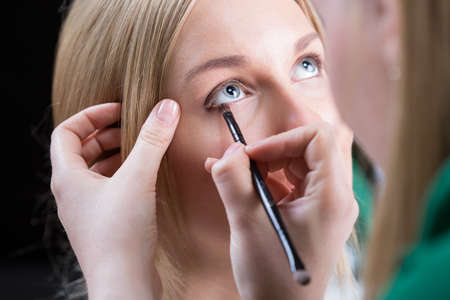 Woman paints the eyes of the bride before the wedding