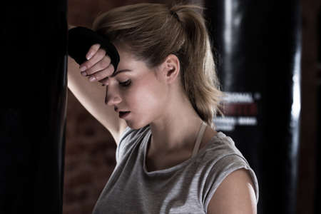 Tired girl next to punch bag, horizontalの写真素材