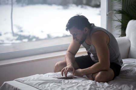 Man sitting on the bed and using digital tabletの写真素材