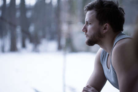 Young man looking through the window and thinkingの写真素材