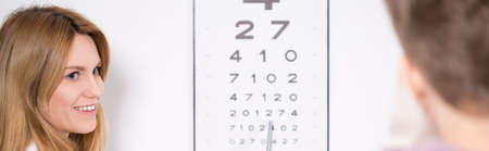 Optician using Snellen test during eye examination