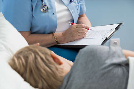Female doctor writing down her notes about little kid