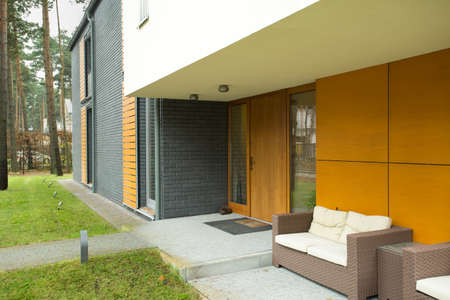 Wicker furniture in front of detached houseの写真素材