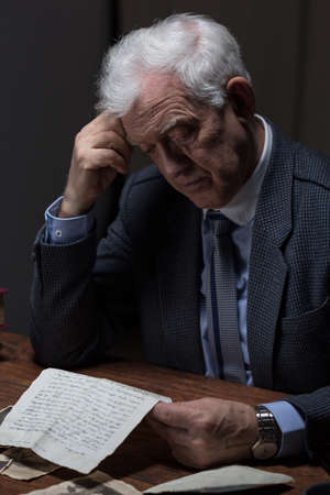 Lonely aged man reading old letter from a loverの写真素材