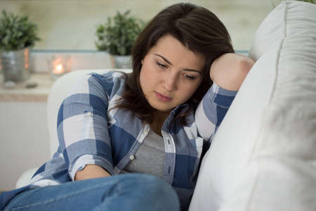 Young concerned woman sitting on psychologist's couch