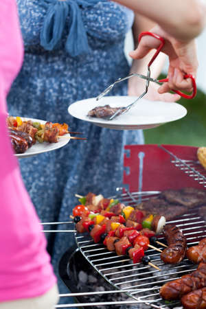 Woman serving char-grilled dinner on barbecue party