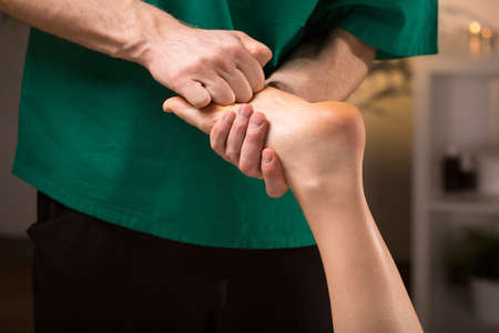 Close-up of male hands doing foot massageの写真素材
