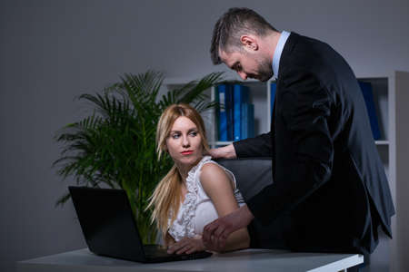 Older handsome employer sexual bullying at work his younger assistantの写真素材
