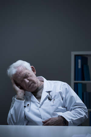 Overworked senior doctor sleeping in the officeの写真素材