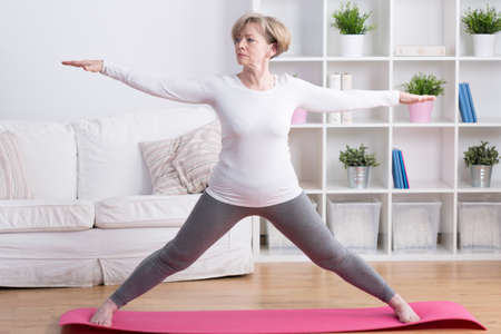 Healthy middle aged woman training yoga at homeの写真素材