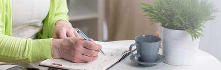 Close-up of female hands writing in calendarの写真素材