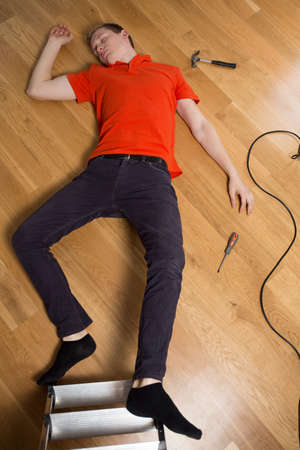 Young man on the floor having dangerous accident at homeの写真素材