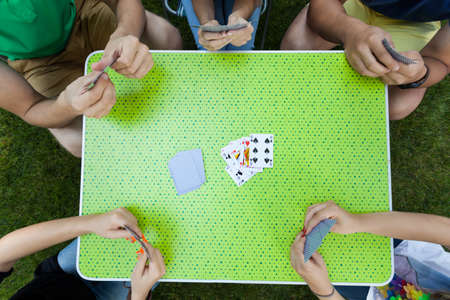 Look from above to young  people playing cards in garden