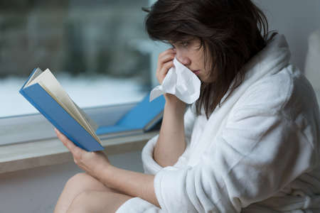 Sensitive young woman reading romance and cryingの写真素材