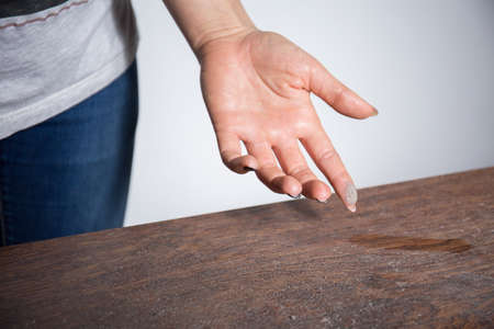 Close-up of dust on woman finger taken from wooden tableの写真素材