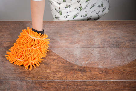 Woman cleaning dusty table with orange cleanerの写真素材