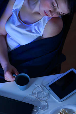 Young sleeping woman holding cup of teaの写真素材