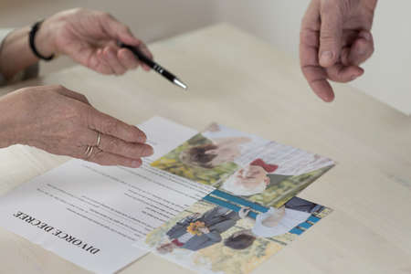 Close-up of betrayed older woman signing divorce decreeの写真素材