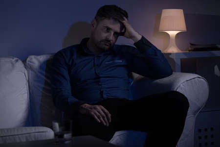 Worried thoughtful man sitting on the sofaの写真素材